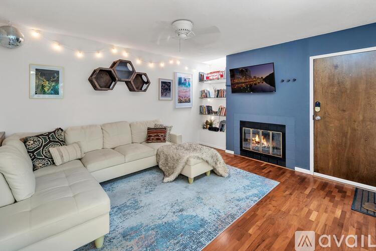 A living room with a white couch and a blue rug.