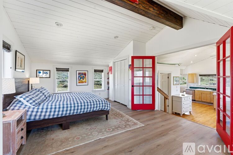 A bedroom with a bed, dresser, and red door.