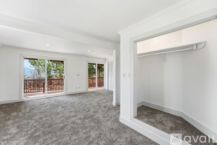 A spacious room with a carpeted floor and a large window overlooking a balcony.