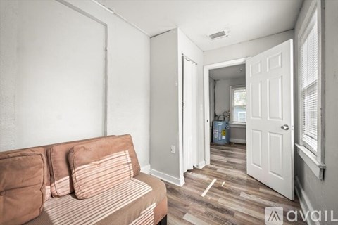 A living room with a striped couch and a doorway leading to another room.