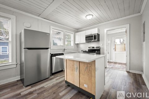 A kitchen with wooden cabinets and a stainless steel refrigerator.