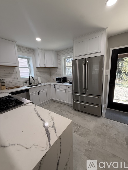 A kitchen with white cabinets and a marble countertop.