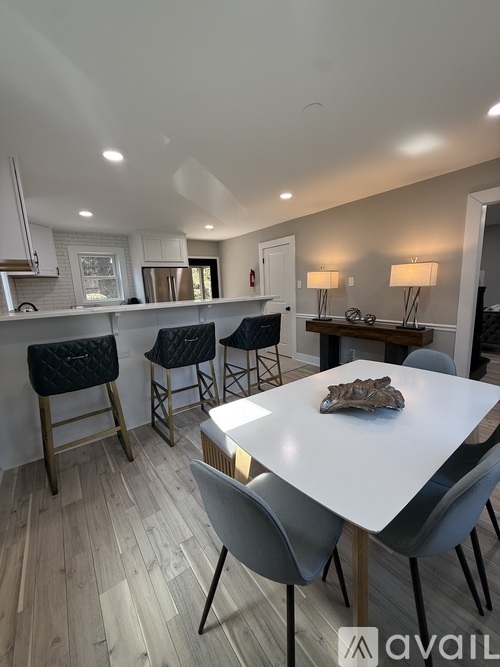 A modern dining room with a white table and grey chairs.