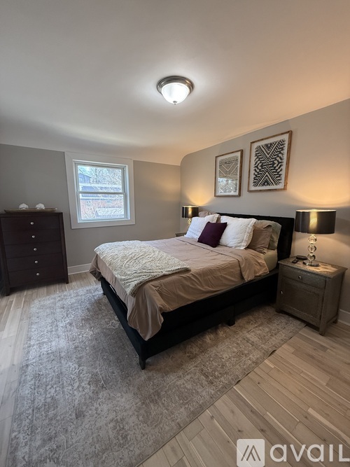 A bedroom with a bed, nightstand, and a window.