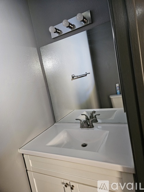A white bathroom sink with a silver faucet and a mirror above it.