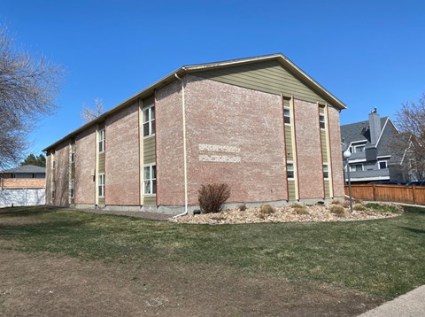 A small brick building with a green roof and a sign on the front.