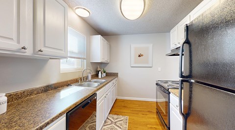 A kitchen with a granite counter top and a refrigerator.