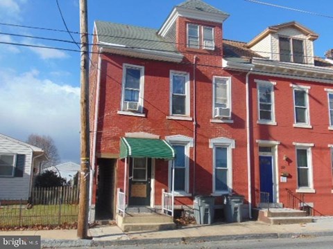 A red brick house with a green awning.