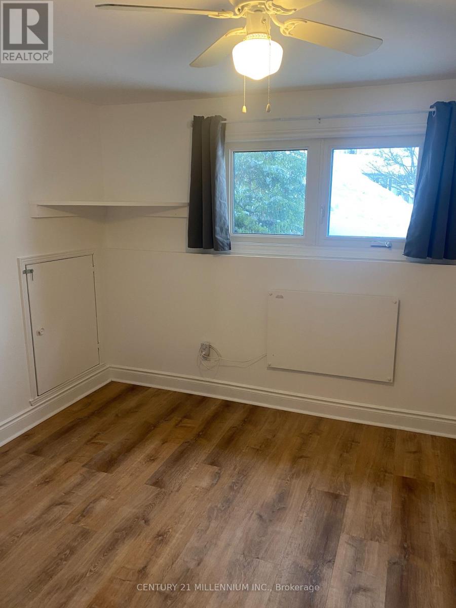 A room with a ceiling fan and a window with a view of trees.