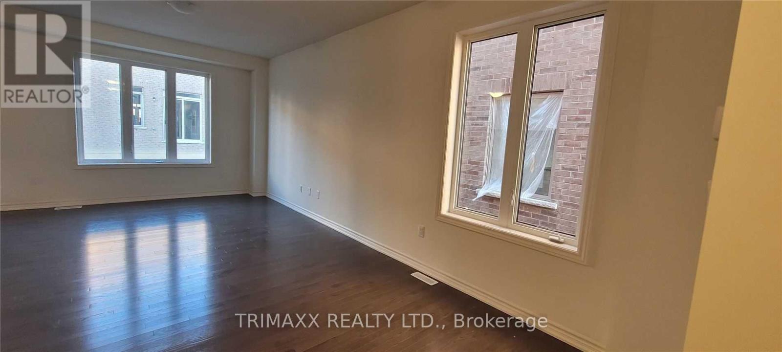 A room with wooden floors and a window showing a brick building outside.