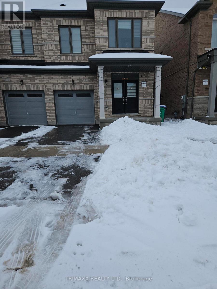 A snow-covered driveway leads to a brick house with a black door.