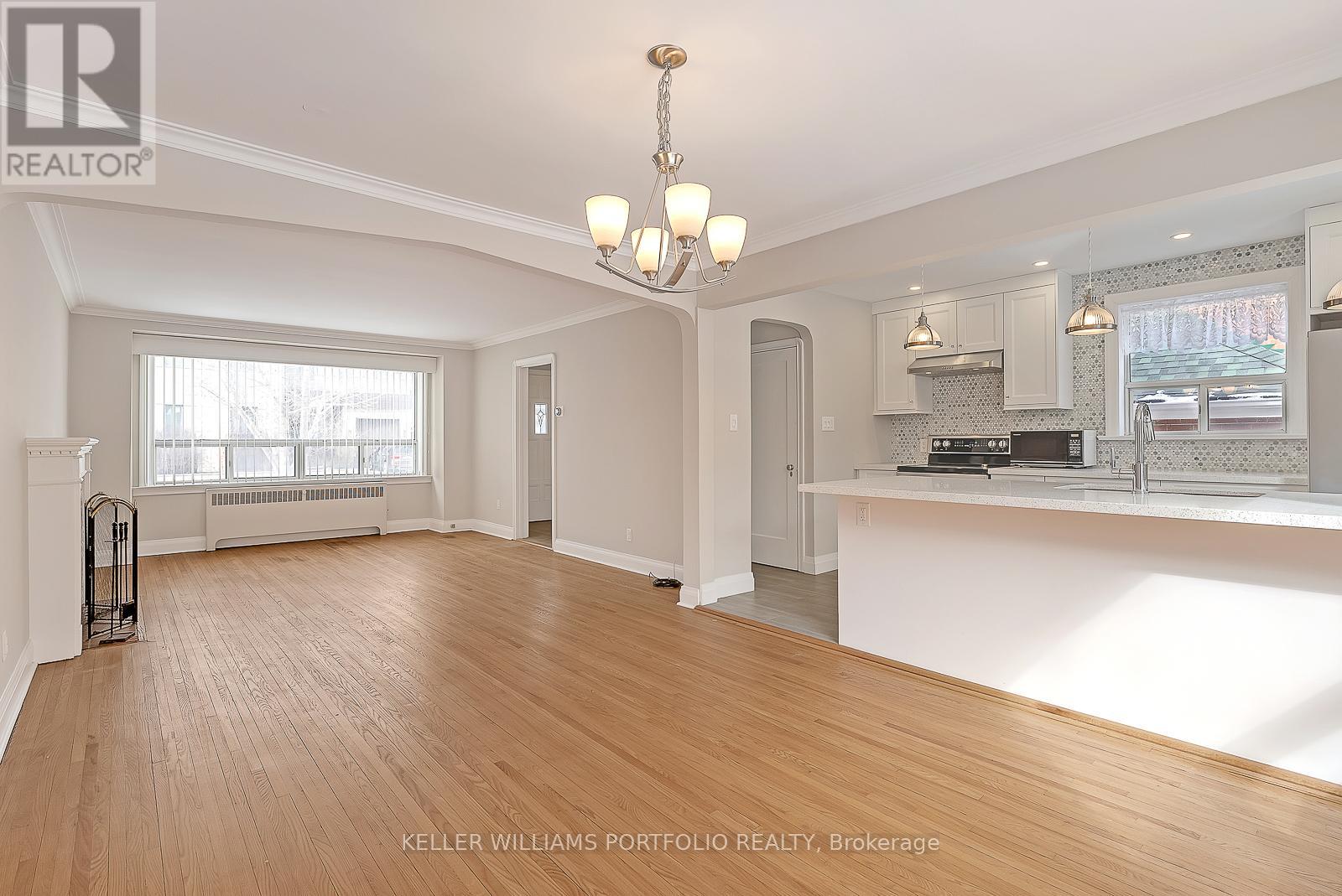 A spacious living room with hardwood floors and a large window.