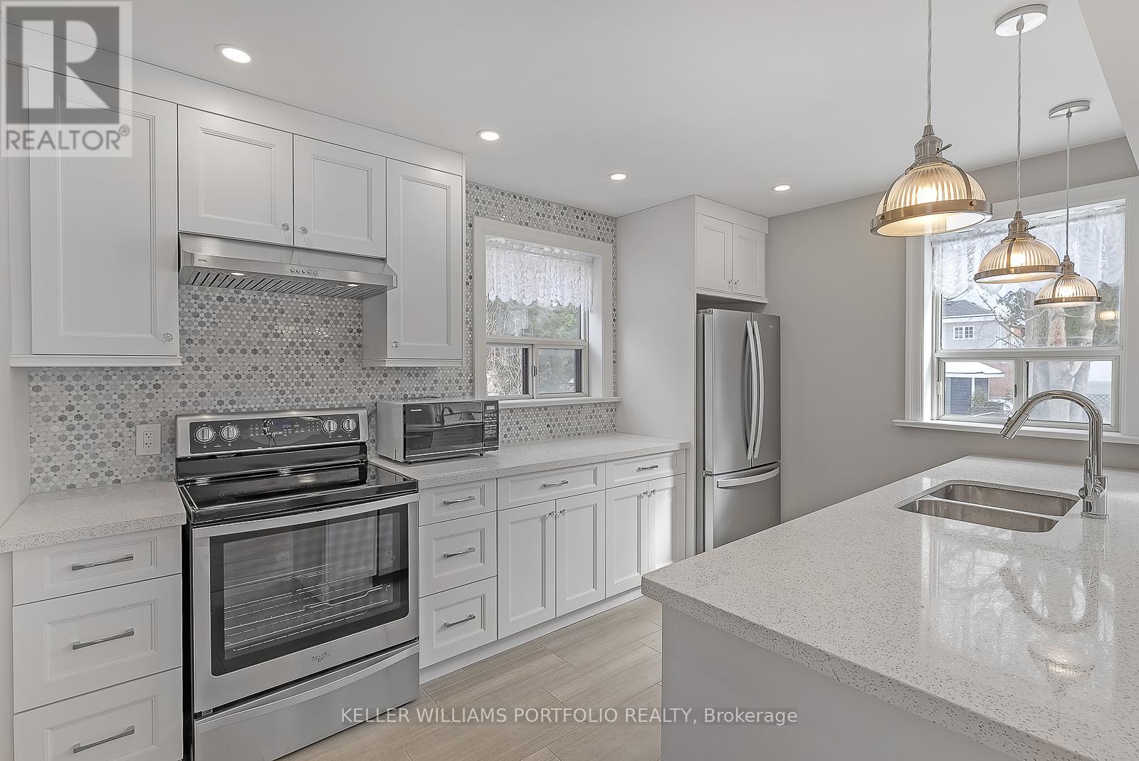 A modern kitchen with white cabinets and stainless steel appliances.