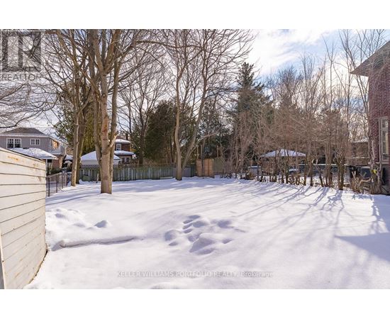 A snow-covered yard with a fence and bare trees.