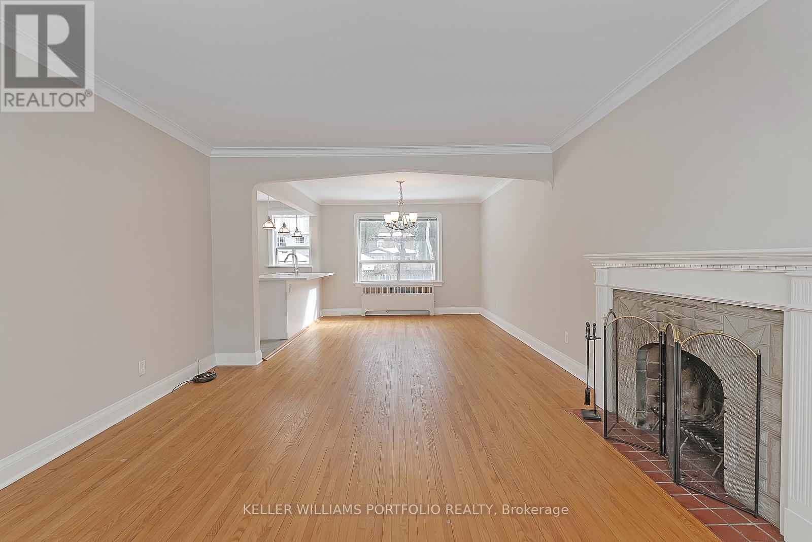 A spacious room with a fireplace and wooden floors.