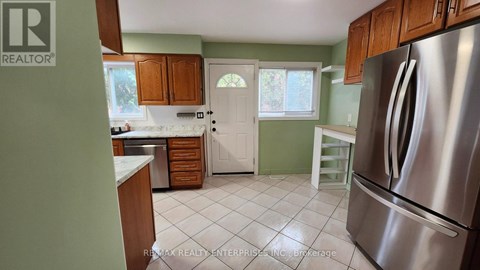 A kitchen with a stainless steel refrigerator and wooden cabinets.