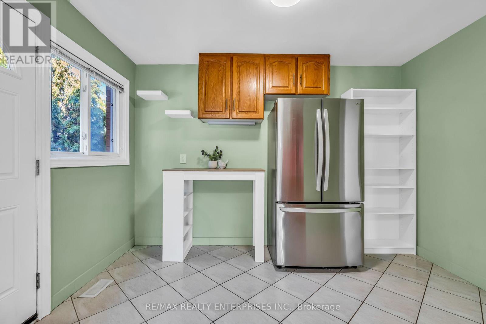 A kitchen with green walls, a white table, and a stainless steel refrigerator.