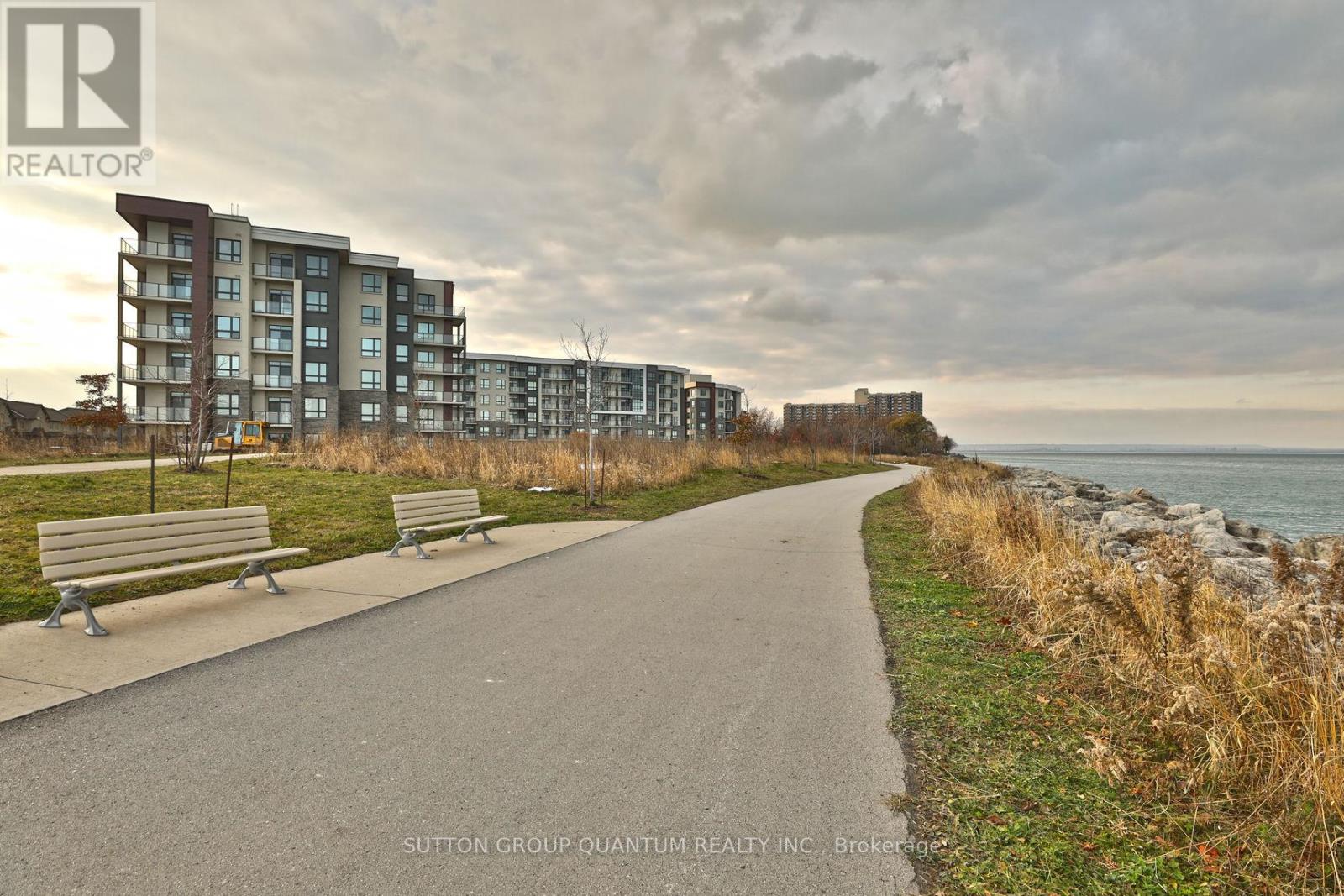 A pathway with benches and apartment buildings in the background.