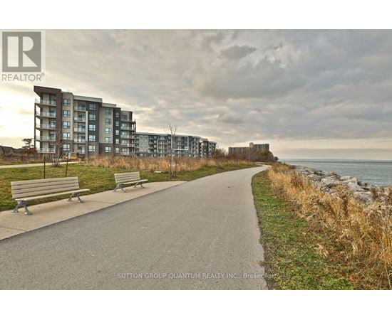 A pathway with benches and apartment buildings in the background.