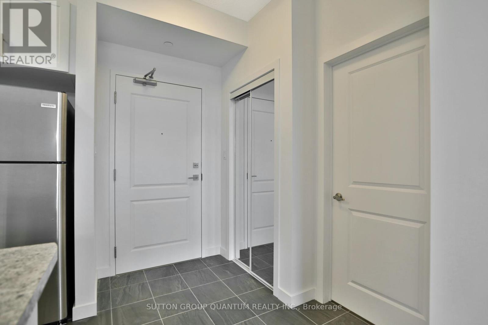 A kitchen with a refrigerator and a door on the left.
