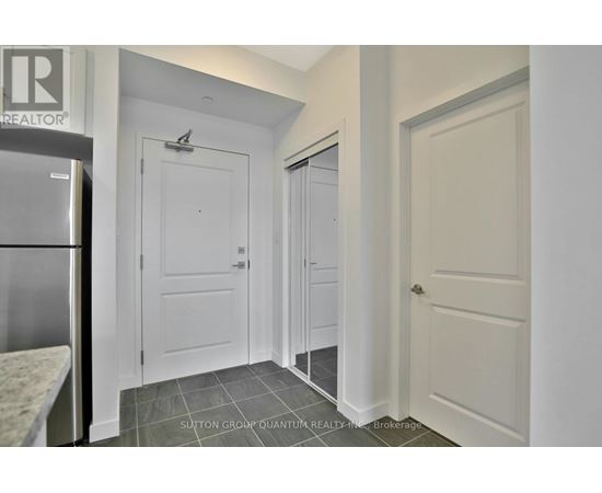 A kitchen with a refrigerator and a door on the left.