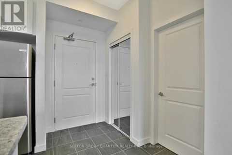 A kitchen with a refrigerator and a door on the left.