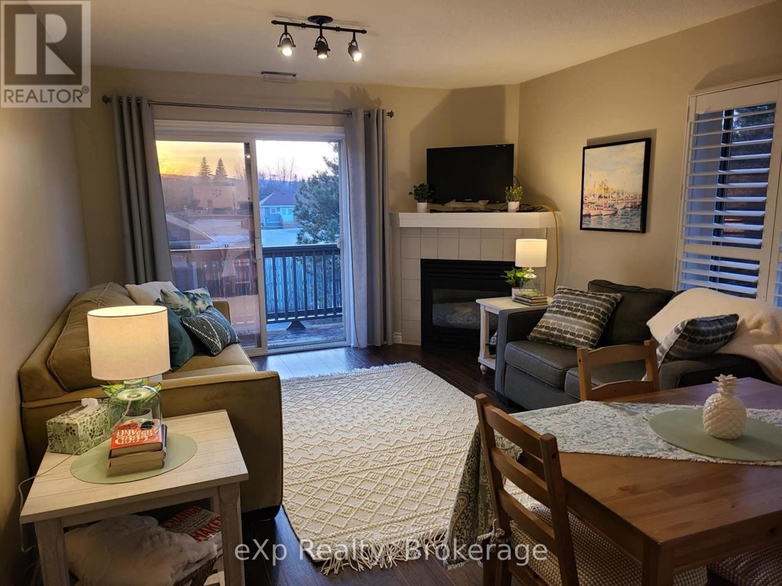 A living room with a fireplace, a couch, a chair, a coffee table, and a television.