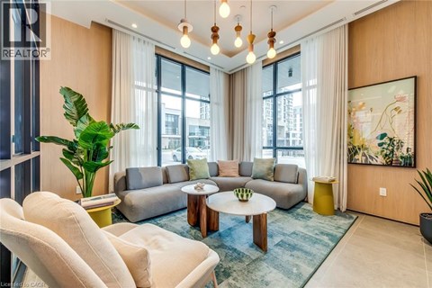A living room with a large window, a grey sofa, a white armchair, a coffee table, and a painting on the wall.