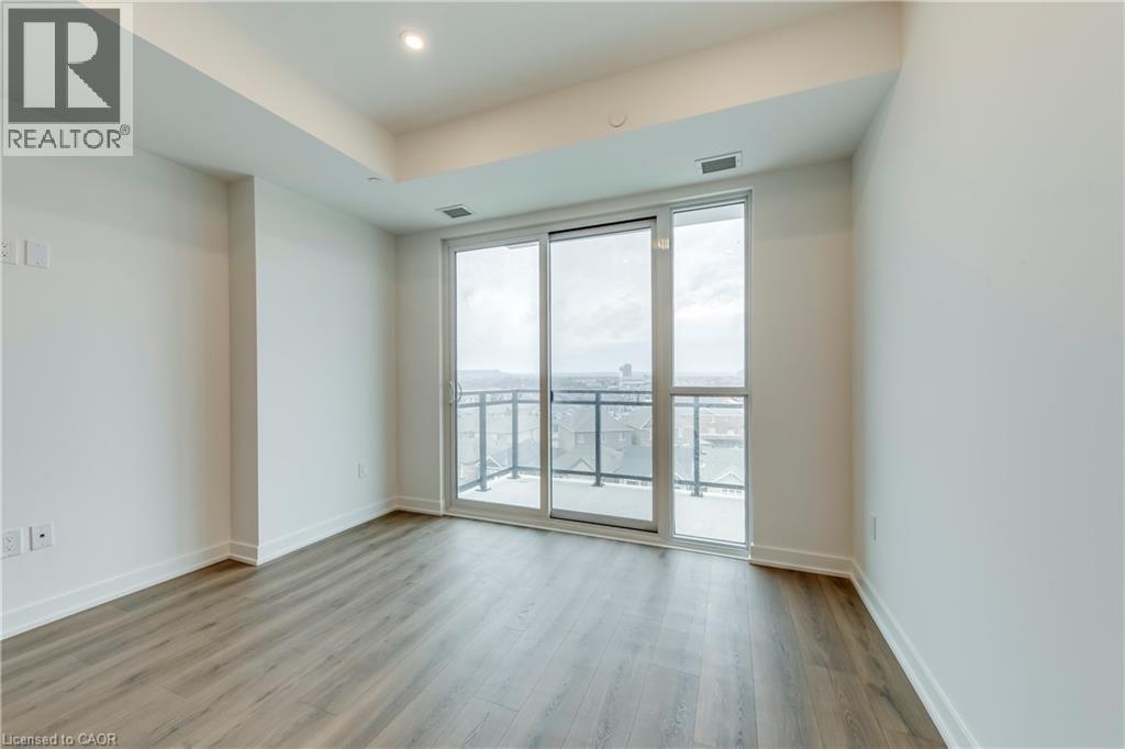 A spacious room with wooden floors and a sliding glass door leading to a balcony.