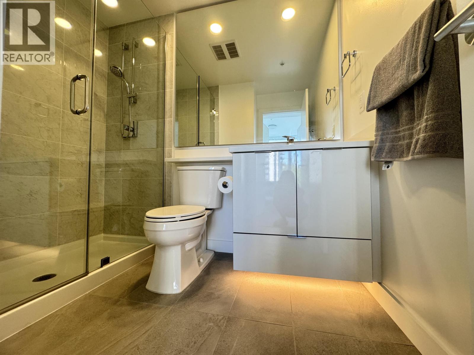 A white toilet sits in a modern bathroom with a glass shower.