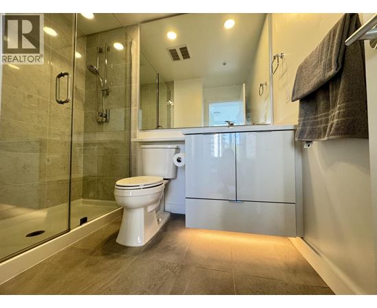 A white toilet sits in a modern bathroom with a glass shower.