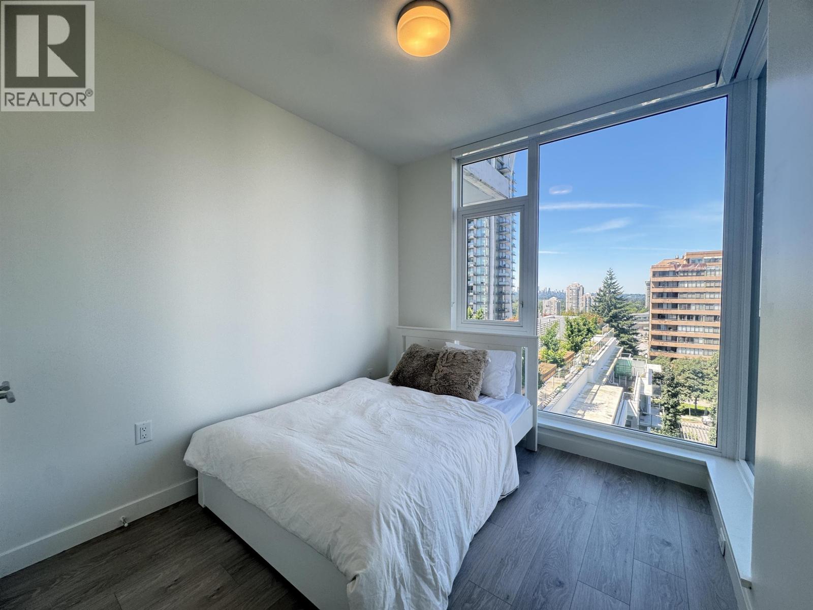 A bedroom with a large bed and a window overlooking a cityscape.