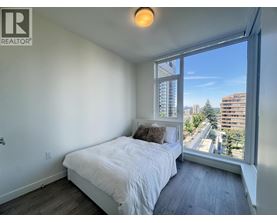 A bedroom with a large bed and a window overlooking a cityscape.