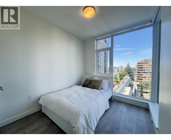 A bedroom with a large bed and a window overlooking a cityscape.