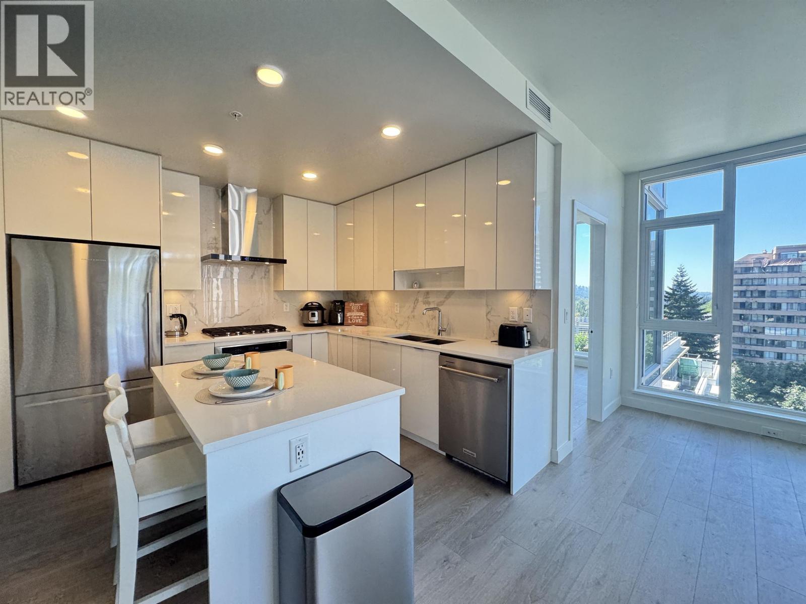 A modern kitchen with a dining table and a view of the city.