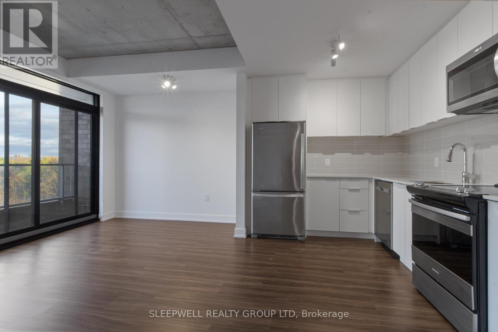 A modern kitchen with wooden floors and stainless steel appliances.