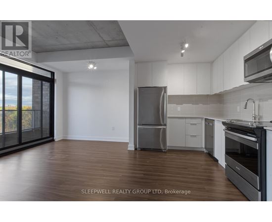 A modern kitchen with wooden floors and stainless steel appliances.