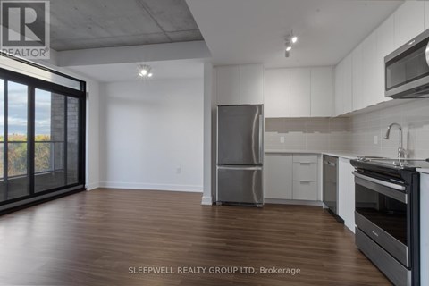 A modern kitchen with wooden floors and stainless steel appliances.