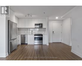 A modern kitchen with stainless steel appliances and wooden flooring.