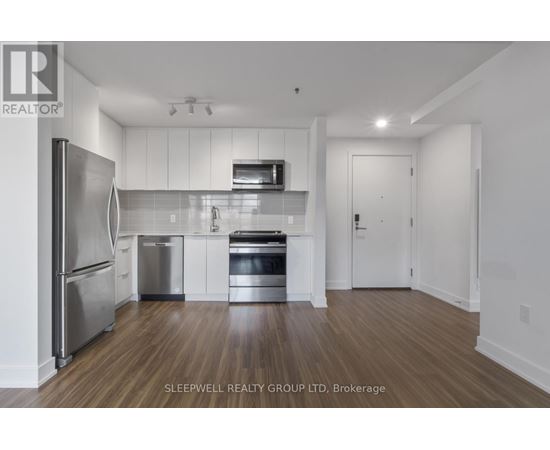 A modern kitchen with stainless steel appliances and wooden flooring.