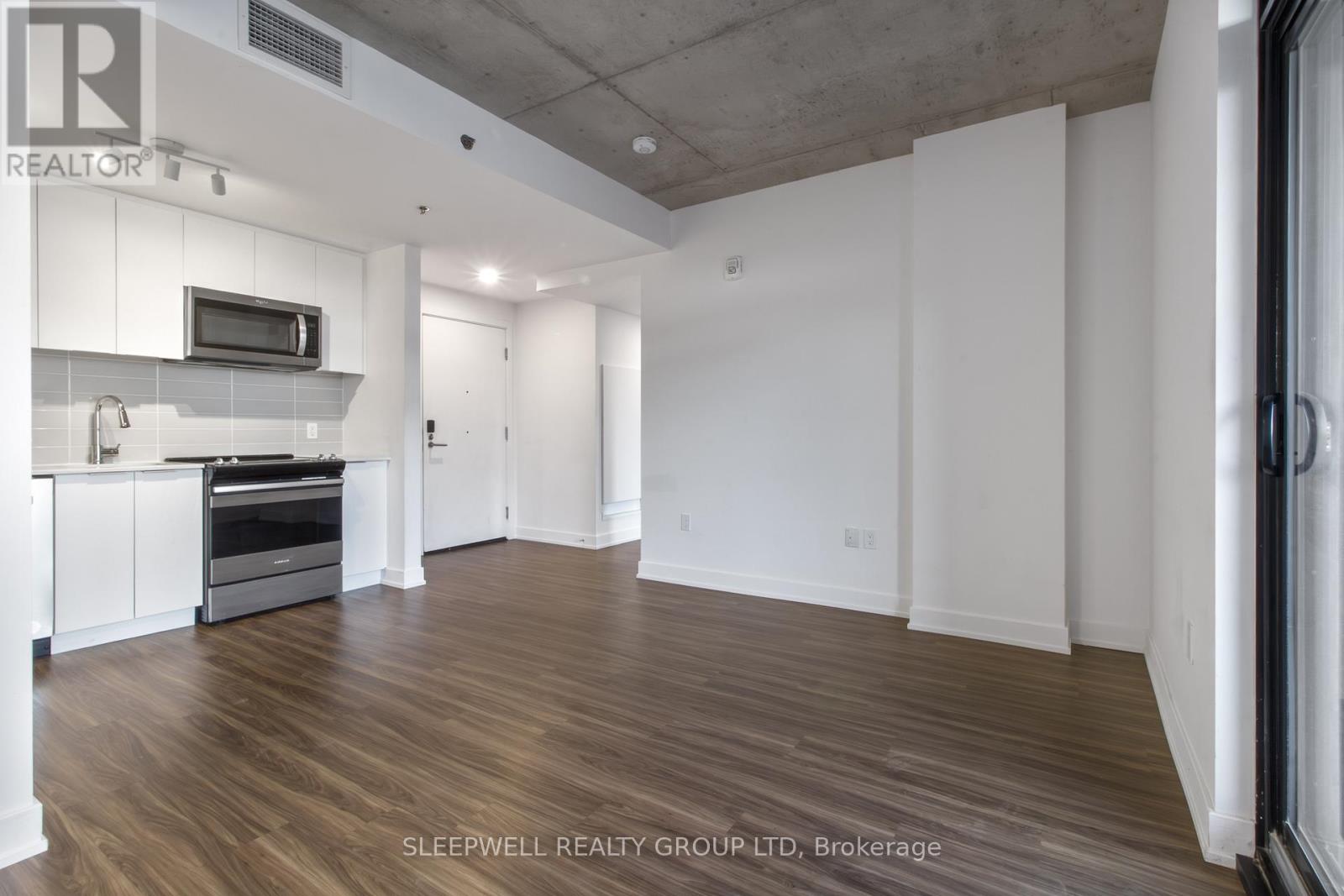A spacious room with wooden flooring and white walls.