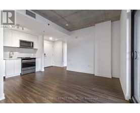 A spacious room with wooden flooring and white walls.