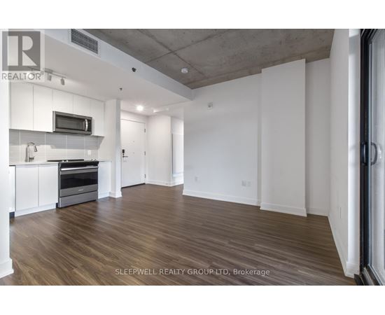 A spacious room with wooden flooring and white walls.