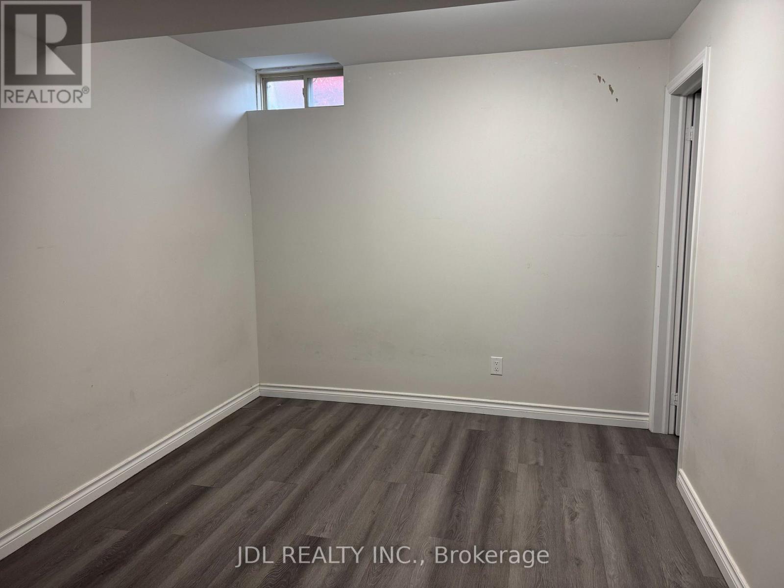A room with wooden flooring and a window.