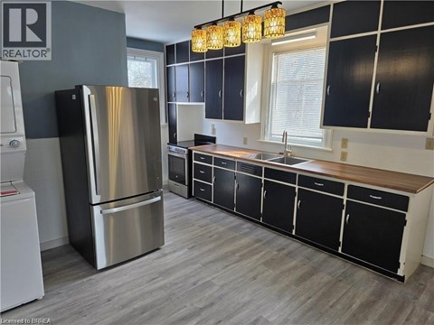 A modern kitchen with a stainless steel refrigerator and black cabinets.