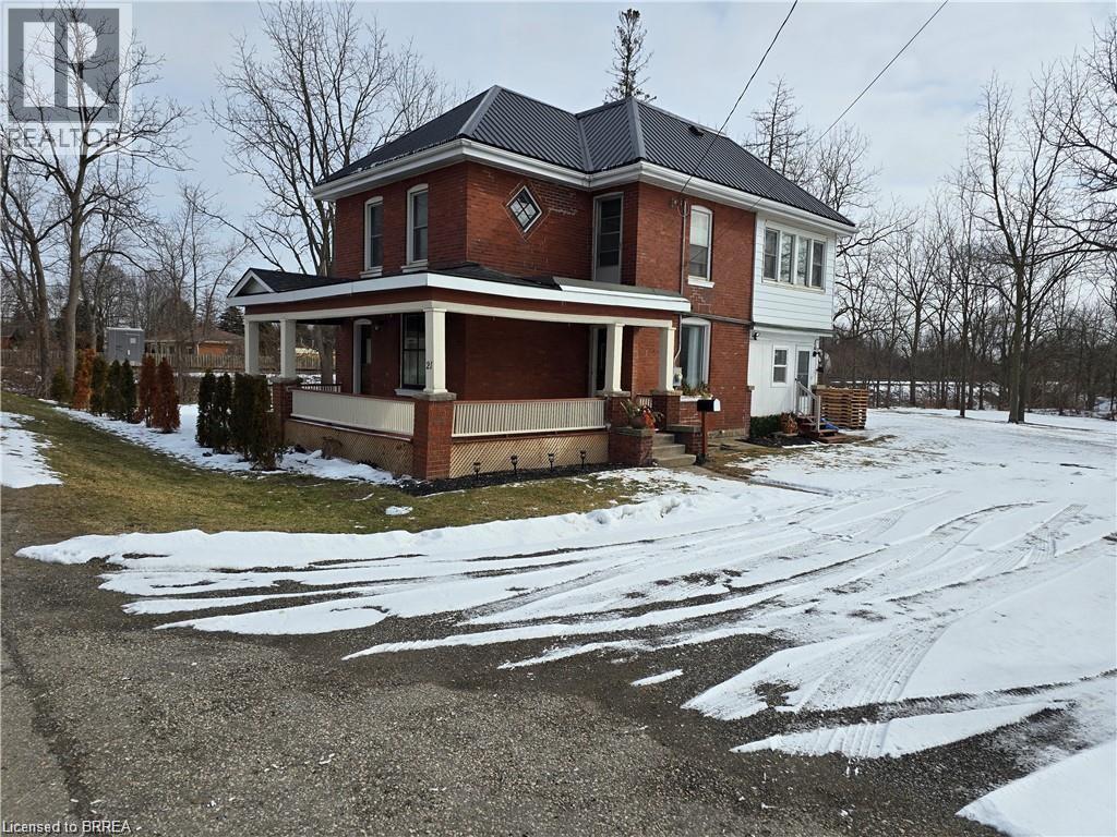 A red brick house with a white porch and a black roof.