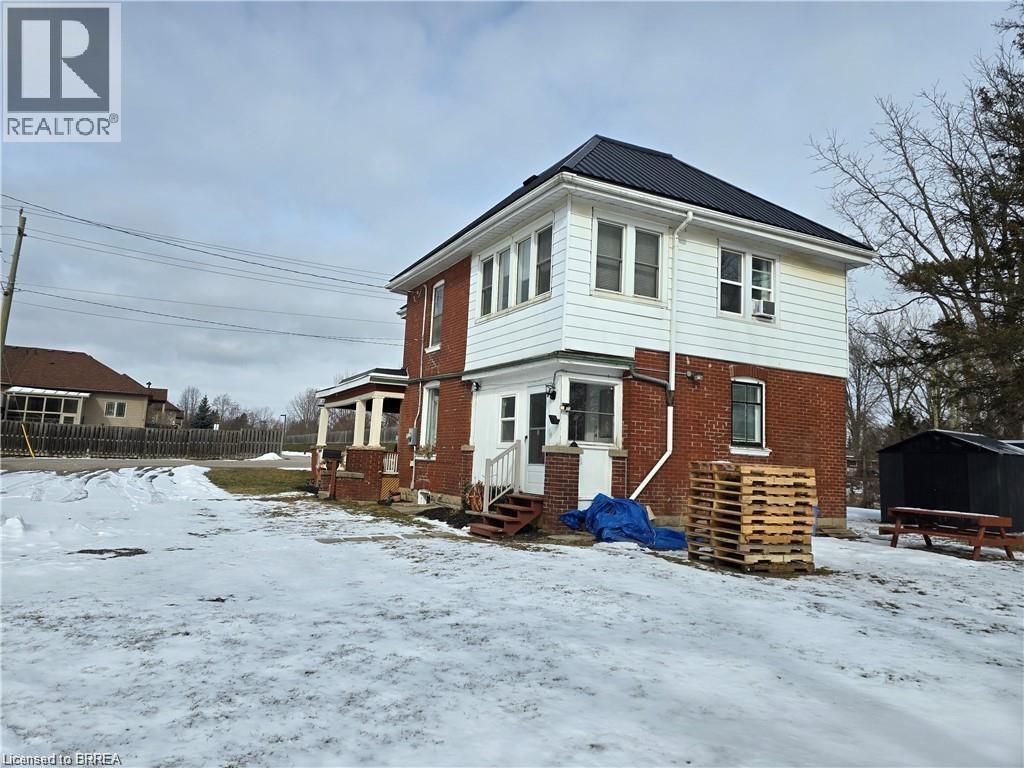 A house with a white and red brick exterior is surrounded by snow.