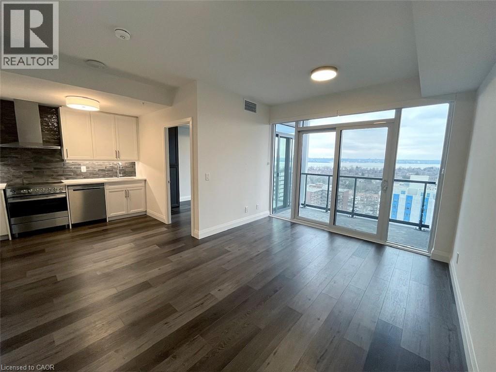 A spacious living room with wood flooring and a view of the outdoors through large windows.