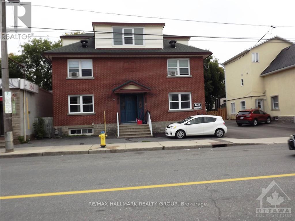 A white car is parked in front of a red brick house.