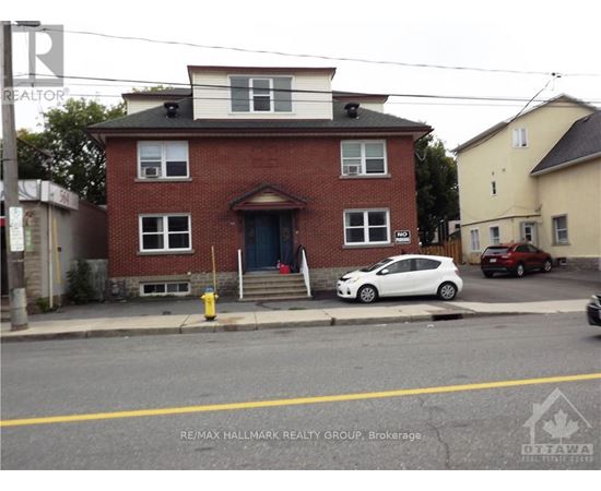A white car is parked in front of a red brick house.